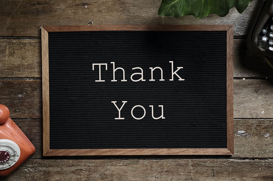 Black and brown wooden Thank You signage on top of brown table