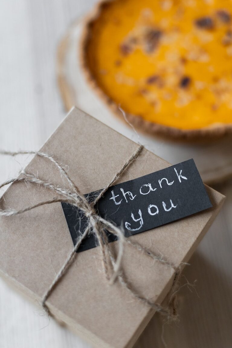 Carton gift box with thank you postcard on table near pie