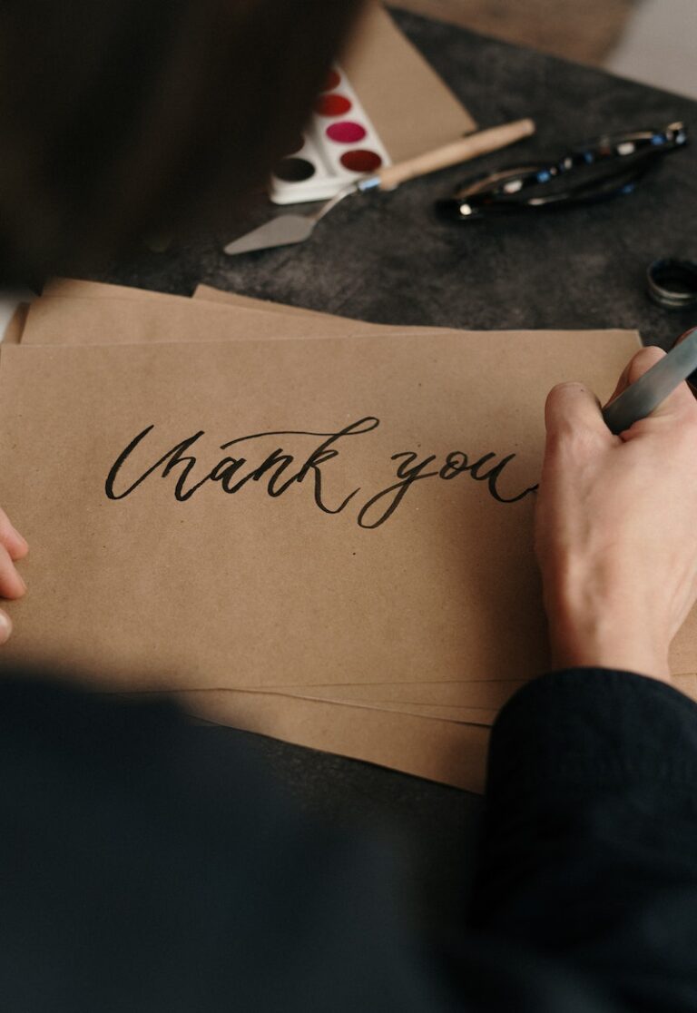 Person Writing Thank You on Brown Printer Paper