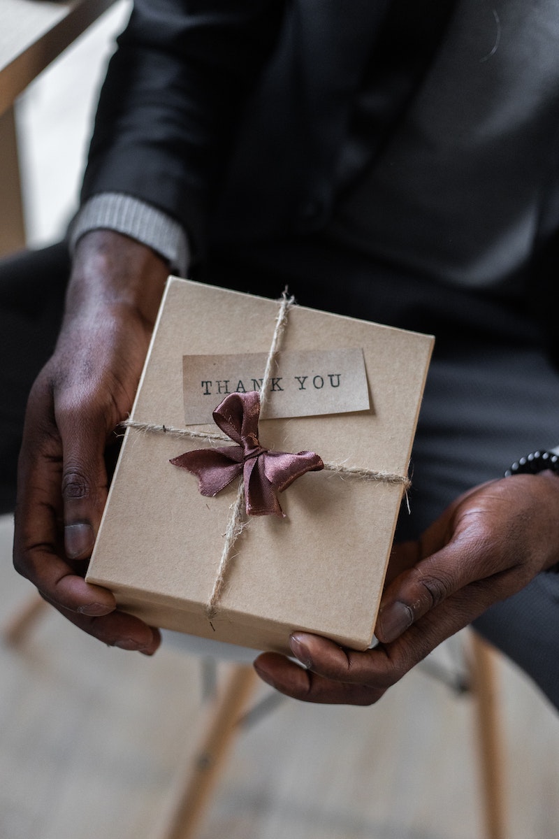 Person holding gift box with thank you note